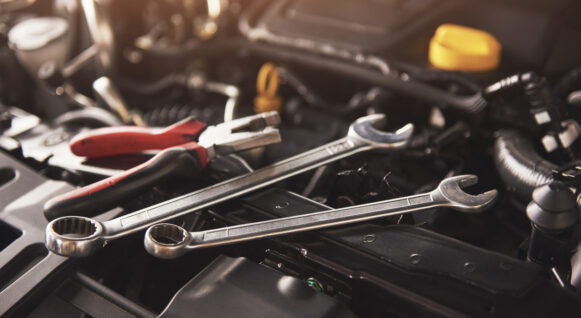 Mechanic hand checking and fixing a broken car in car service garage.